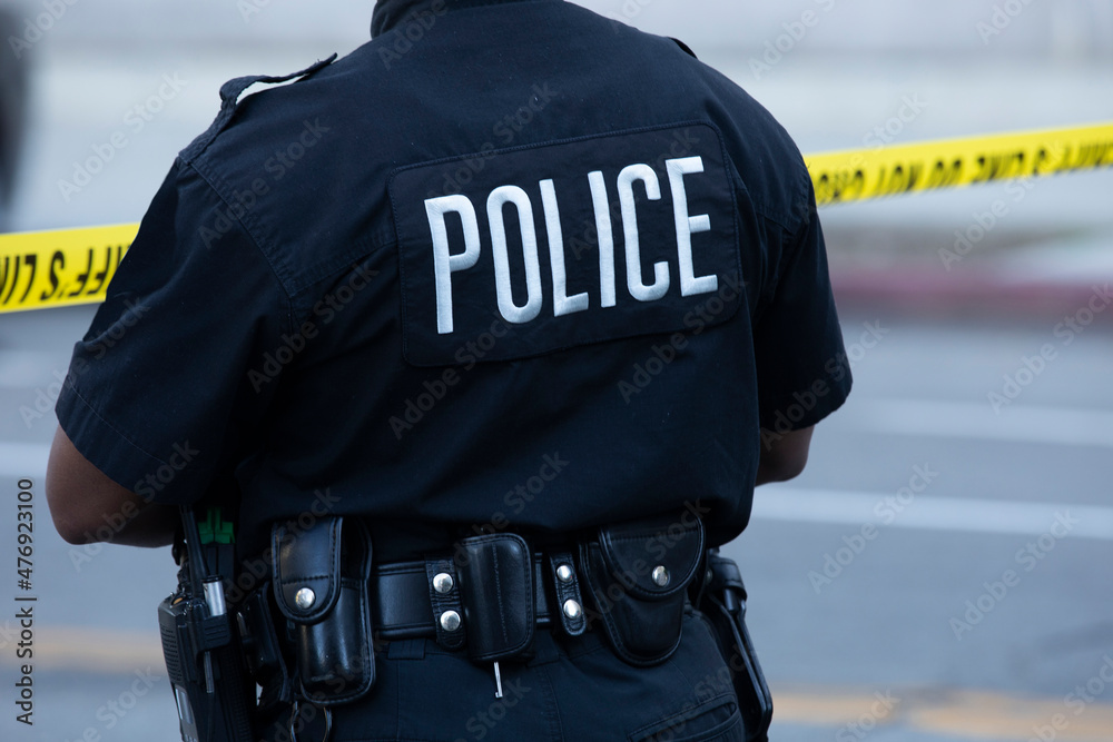 Detailed view of police uniform and cordon tape sealing off an active crime scene. Detailed view of police uniform and cordon tape sealing off an active crime scene.