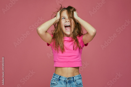 Joyful child girl naughty hooligan ruffle long unbrushed disheveled hairs, scream, having fun. Positive emotions photo