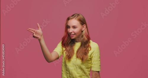 Confident young pretty girl with gun gesture searching for target, point by finger, shooting with hand pistol to camera
