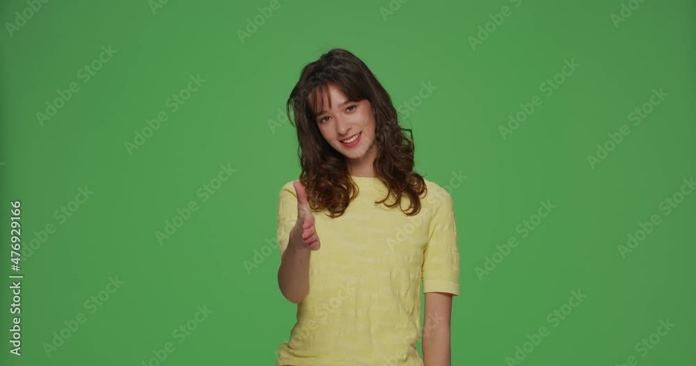 Smiling young girl extending hand for handshake introducing greeting offering business collaboration on green background Smiling young girl extending hand for handshake introducing greeting offering business collaboration on green background