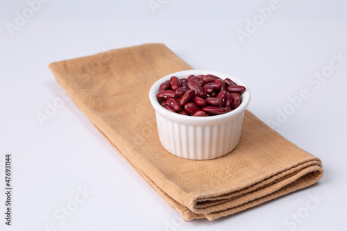 red kidney bean in white bowl on cloth and white background studio shot
