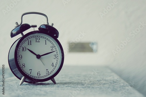 Retro alarm clock on table near swimming pool with sun light blurred background , interior object for decoration 