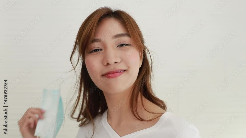 Portrait of a healthy woman, taking off her mask, smiling and in a good mood, actively looking at the camera : Bright-faced Asian woman wearing a mask to prevent flu and COVID-19. Portrait of a healthy woman, taking off her mask, smiling and in a good mood, actively looking at the camera : Bright-faced Asian woman wearing a mask to prevent flu and COVID-19.