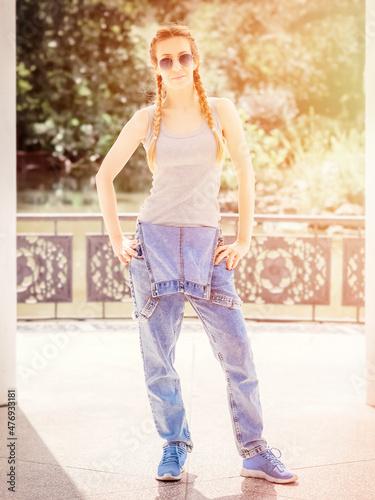 Cute fairhaired girl with two pigtails stands in the park. Post-processing. Artistic effect photo