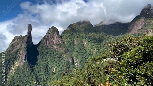 Vibrant Brazilian panoramic landscape of mountain range Serra dos Orgaos in Teresopolis with Dedo de Deus, Gods finger peak, in the middle and clouds behind revealing Rio de Janeiro behind photo