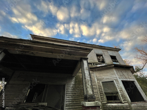 Old creepy scary wooden overgrown abandoned mansion sky and wide view