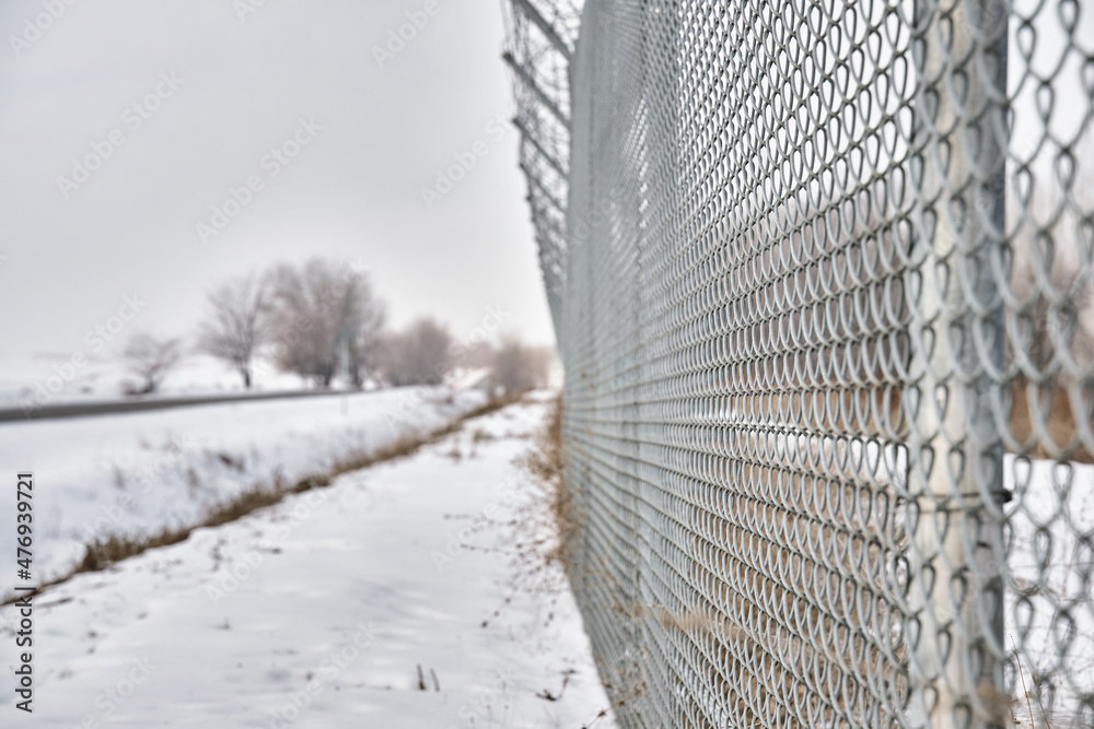 Close up of barbed wire fence on border in winter. Private secured object near highway. Maximum security detention facility. Closing for quarantine. Unauthorized entry is prohibited.