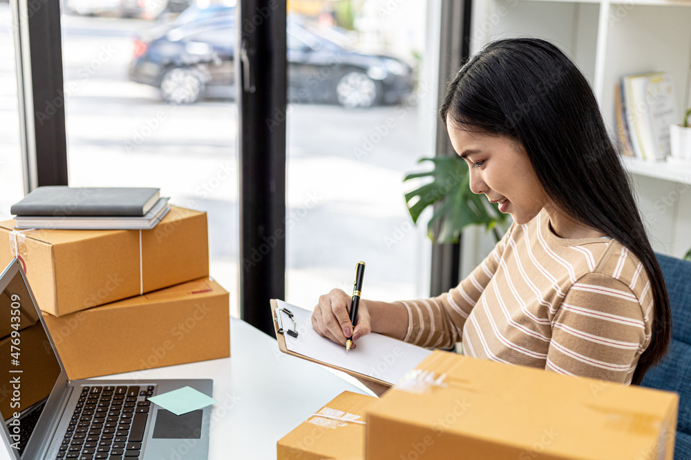 The owner of the online store is checking the purchase amount from the laptop and preparing the delivery, parcel for packing the goods. Online selling and online shopping concepts. The owner of the online store is checking the purchase amount from the laptop and preparing the delivery, parcel for packing the goods. Online selling and online shopping concepts.