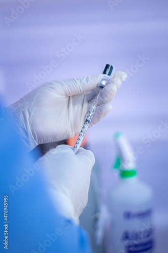 Manos de enfermera sosteniendo jeringa y ampolla photo