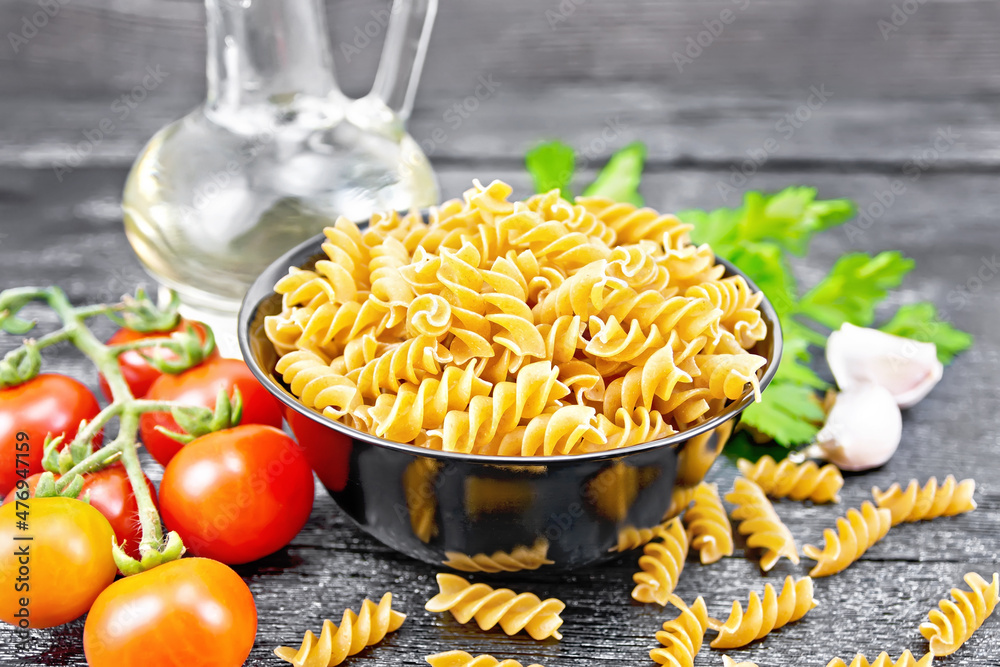 Fusilli whole grain in bowl with vegetables on board