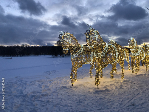 glowing figures of horses in the snow field.decoration of the city for the winter christmas holiday. dark forest and light in the park