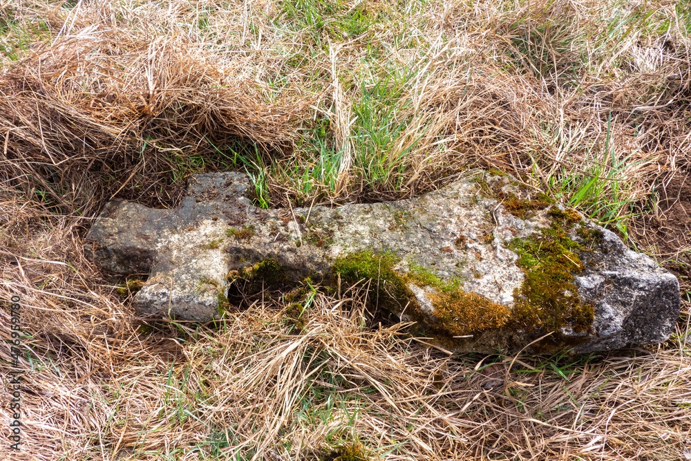 Religious cross lying in the grass in a abandoned graveyard Religious cross lying in the grass in a abandoned graveyard