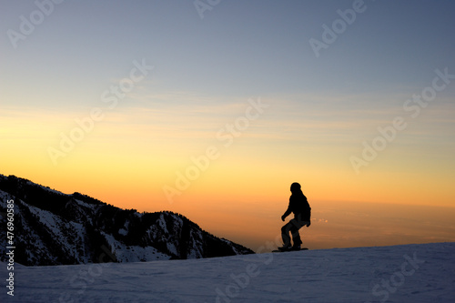 Alpine ski resort. The contours of skateboarders and skiers against the backdrop of a beautiful cloudy sky. Sunset.