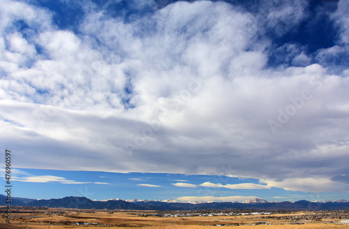 A panoramic view on a sunny day over farmland and the front range of the Colorado Rocky Mountains, as seen from Broomfield, Colorado
