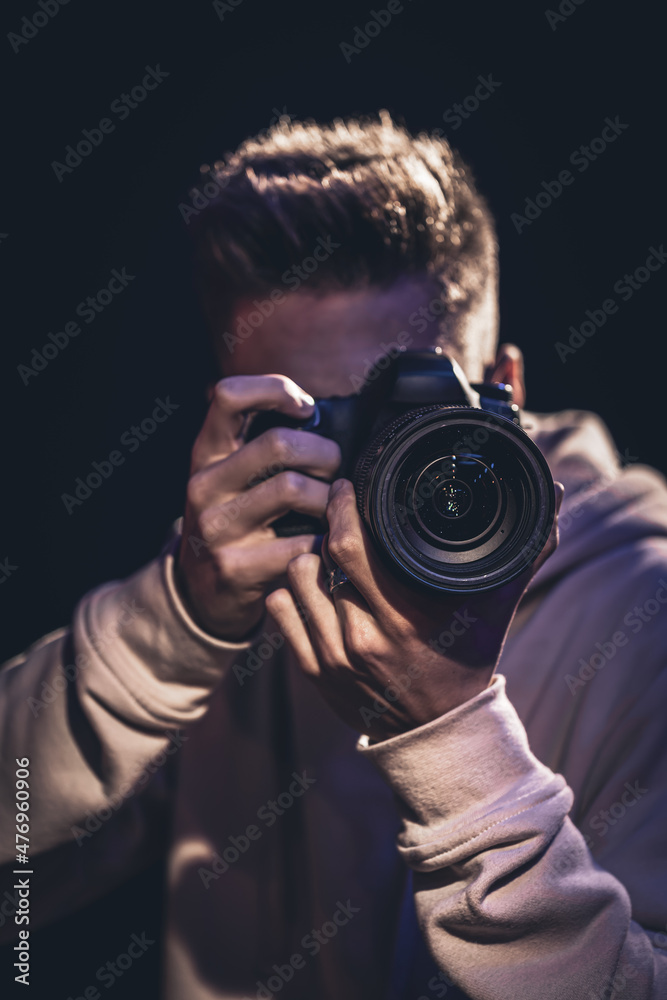A man photographer with a camera takes a photo in the dark. A man photographer with a camera takes a photo in the dark.