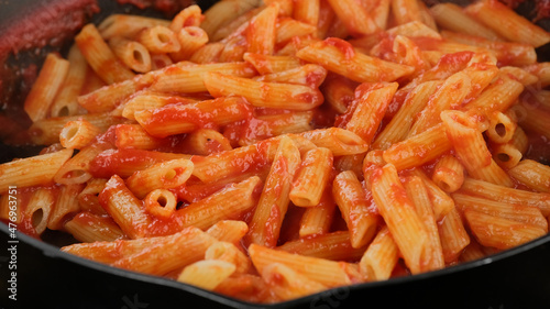 Pasta with tomato sauce in pan, close up. Cooking traditional italian dinner
