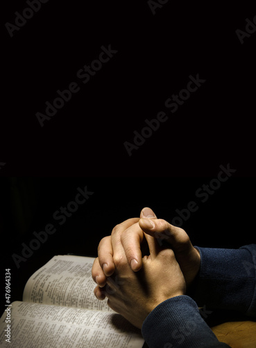 Hands folded in prayer over Scriptures