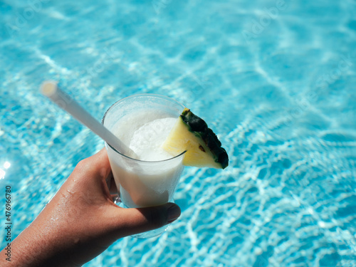 Beautiful glass with a refresh cocktail and a pretty woman on the background of the swim pool. Top view, close-up. Vacation and travel concept. Moments of celebration