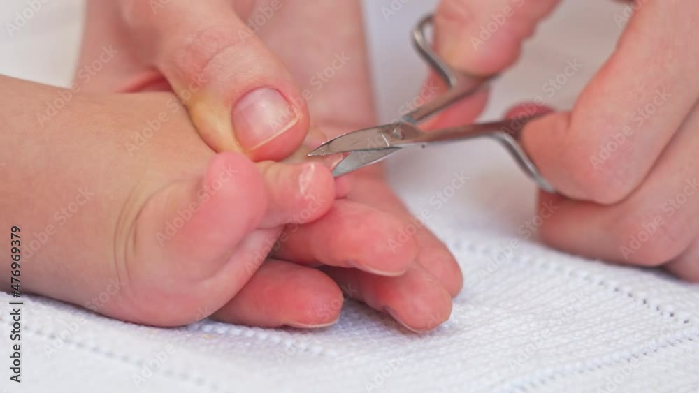 Mom cuts toenails of sleeping baby, close up Mom cuts toenails of sleeping baby, close up