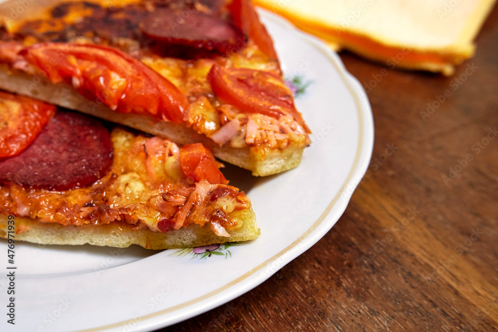 Pieces of pepperoni pizza on a white plate close up Pieces of pepperoni pizza on a white plate close up