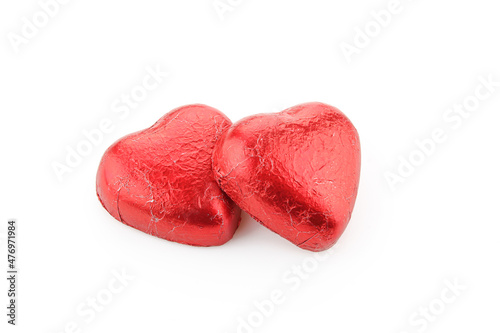 Pair of heart shaped chocolate candies wrapped in red foil isolated on white background