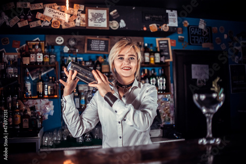 Experienced girl bartending demonstrates his skills over the counter while standing near the bar counter in bar photo