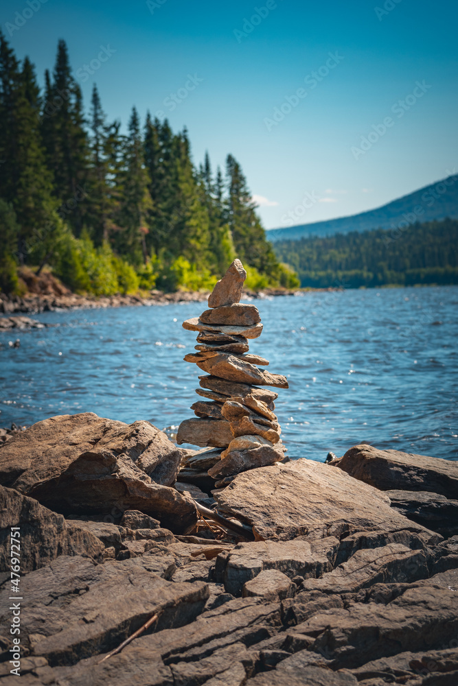 Cairn of stones on the shore of a mountain lake under blue summer sky Cairn of stones on the shore of a mountain lake under blue summer sky