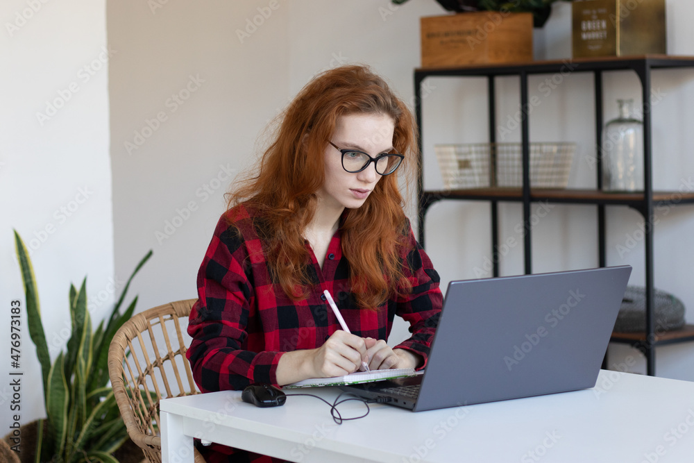 young red-haired girl works remotely from home young red-haired girl works remotely from home