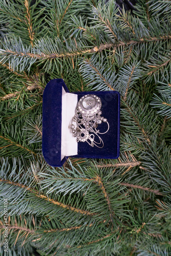  A box with a gift  a silver pendant  lies on the branches of a Christmas tree  photo indoors