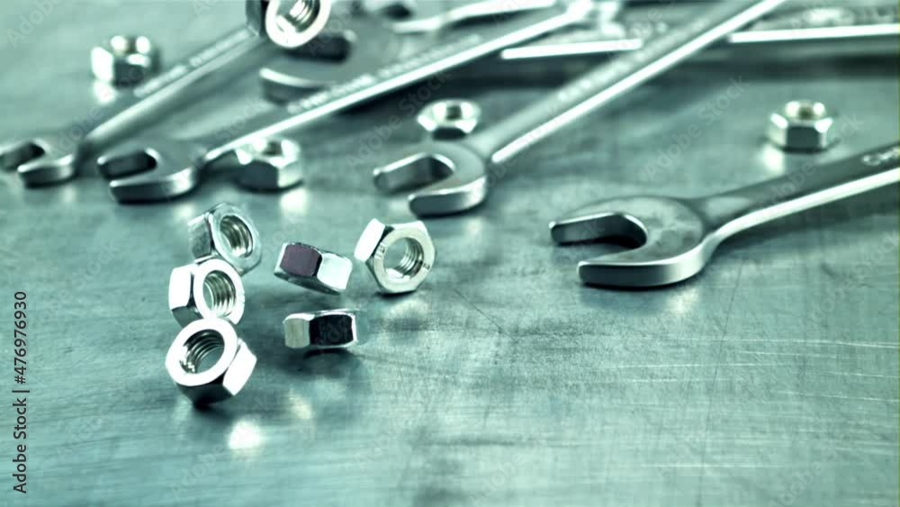 Nut bolts fall on the table. On a gray background. Filmed is slow motion 1000 frames per second. High quality FullHD footage