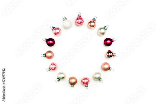 Circle arrangement of pink and white Christmas baubles against white background. Round frame of ball ornament. Top view, flat lay, copy space.