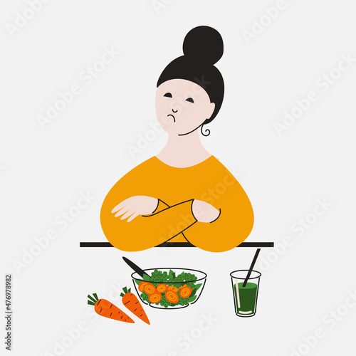 Displeased girl sitting in front of a plate of salad