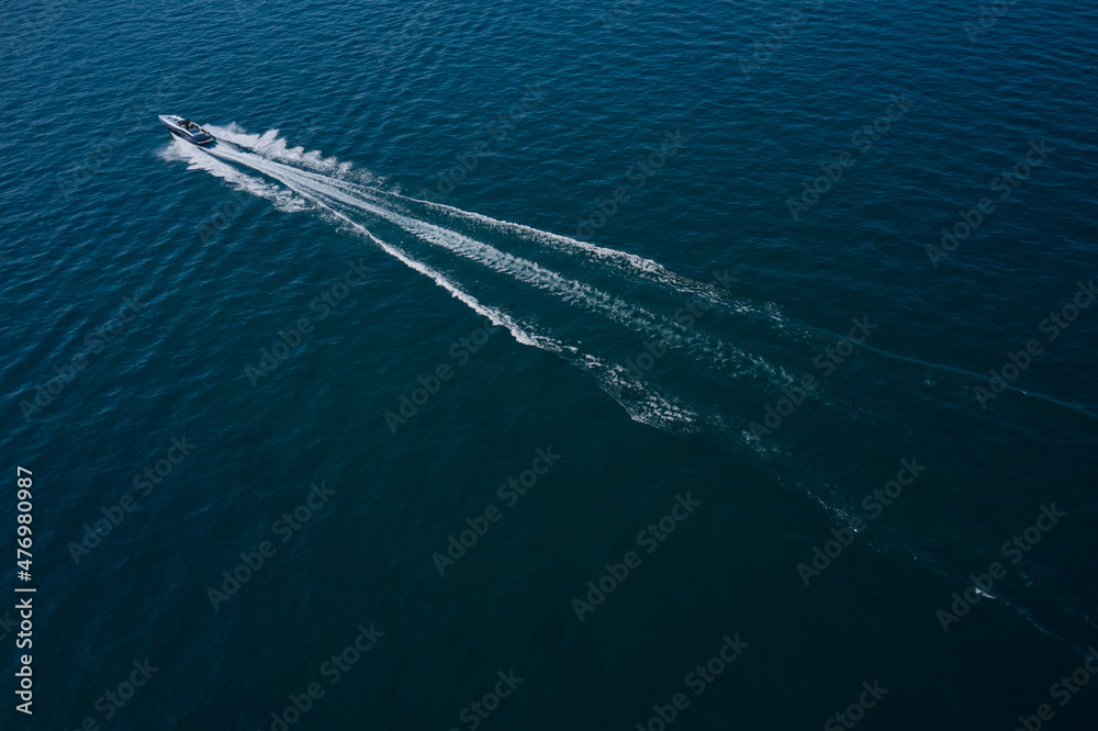 High-speed luxury boat diagonal movement on dark blue water. Boat performance fast movement on the water aerial view. High-speed luxury boat diagonal movement on dark blue water. Boat performance fast movement on the water aerial view.