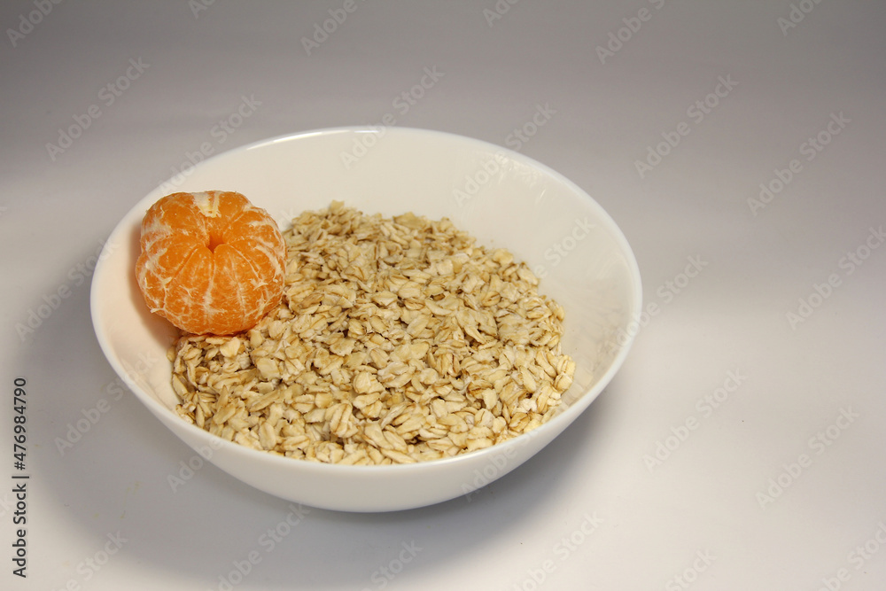 Oatmeal with whole tangerine. In a white plate. Oatmeal with whole tangerine. In a white plate.