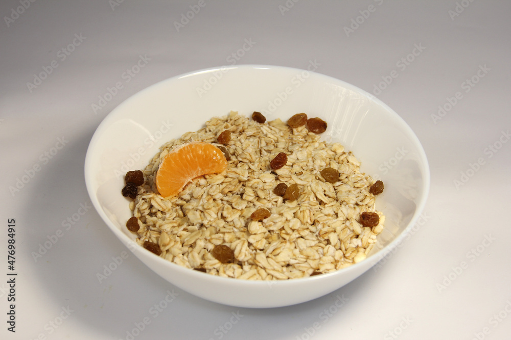 Oatmeal with tangerine slices and raisins. In a white bowl. Oatmeal with tangerine slices and raisins. In a white bowl.