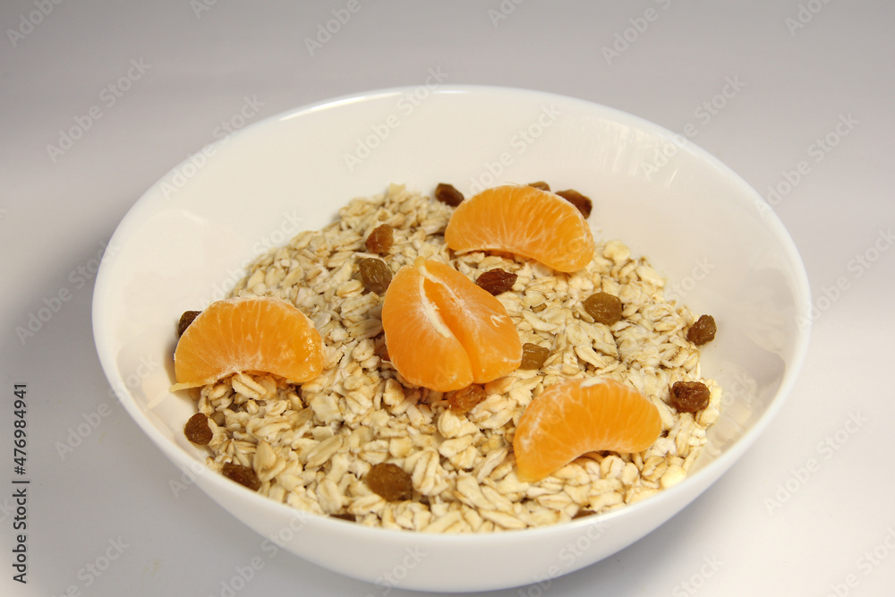 Oatmeal with tangerine slices and raisins. In a white bowl. Oatmeal with tangerine slices and raisins. In a white bowl.