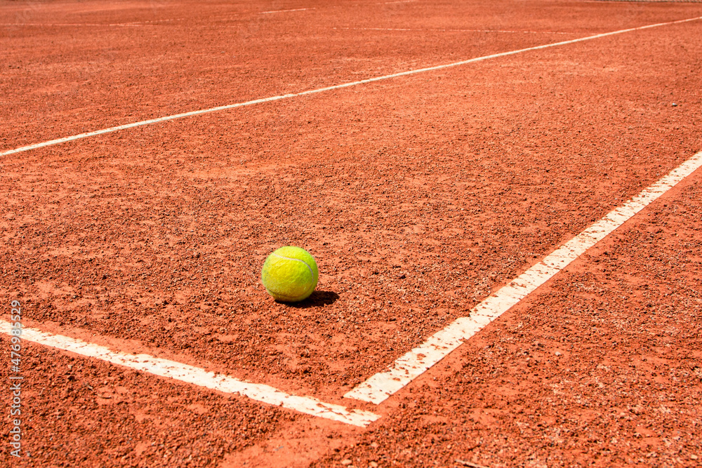 A tennis ball on a dirt court. bright sunny day. vivid colors