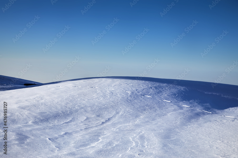 Landscape of snowy hill in the mountains and blue sky