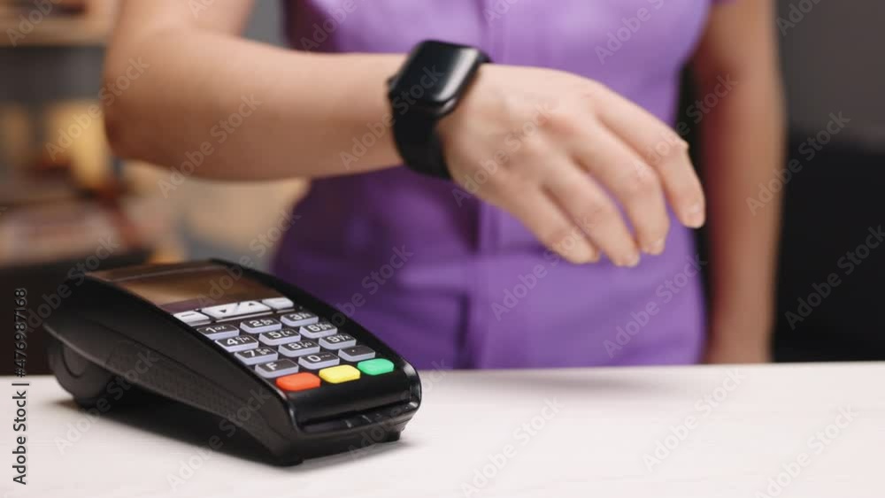 Customer paying with NFC technology by smart watch contactless on terminal in modern cafe. E-money at cashless wallet. Pay by smart watch. Business reopen after covid coronavirus lockdown