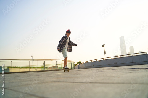 teenage asian boy skateboarding outdoors