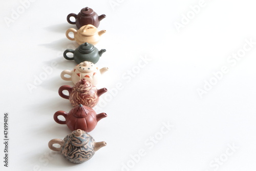 Small decorative teapots. Brown, beige, tile and green color teapots. Tea pots in a row. Chinese traditional clay teapot on the whitee ground. Copy space for text and list. photo