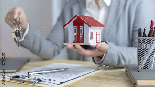 Sales manager or salesperson holds a demo house and has a home purchase contract with keys to deliver to customer buys a house, Sales Service, Home salesman with insurance.