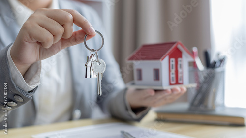 Sales manager or salesperson holds a demo house and has a home purchase contract with keys to deliver to customer buys a house, Sales Service, Home salesman with insurance.
