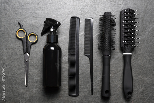 Hairdressing tools and accessories on the black stone flat lay background.