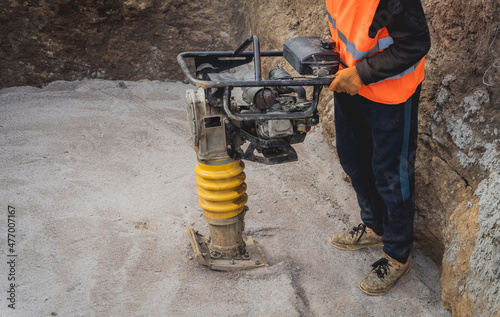 Worker uses a portable vibration rammer at construction of a power transmission substation