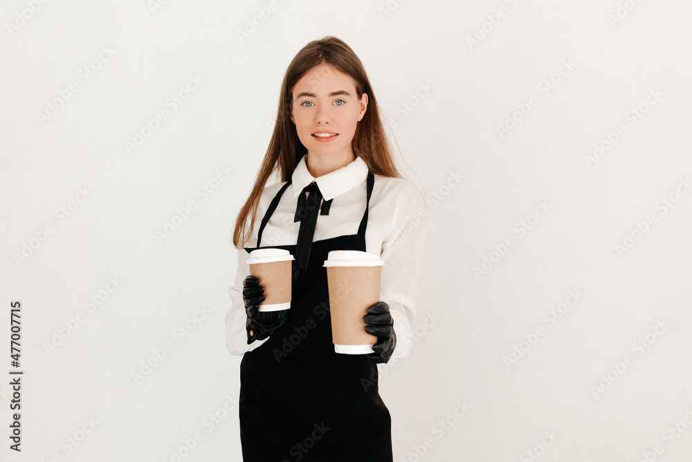 A cute waitress with straight hair in a uniform, offering two paper cups of hot coffee to the camera, on white background A cute waitress with straight hair in a uniform, offering two paper cups of hot coffee to the camera, on white background