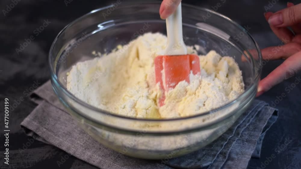 Kneading shortbread dough in the glass bowl with silicone spatula. Mixing liquid and dry ingredients together. Baking at home Kneading shortbread dough in the glass bowl with silicone spatula. Mixing liquid and dry ingredients together. Baking at home