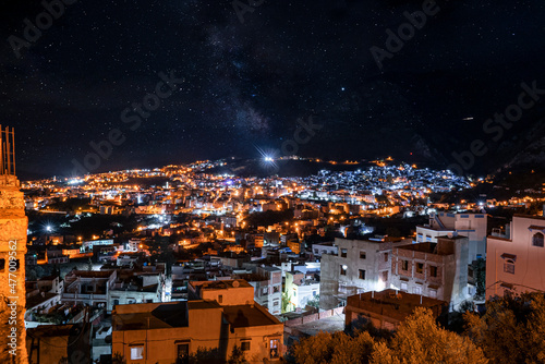 High angle view of lit residential buildings in Chefchaouen old town under the dark night sky © Aerial Film Studio