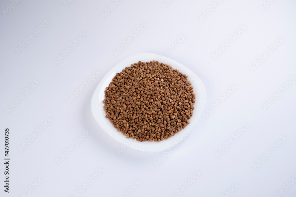 Buckwheat in a white plate on white background, top view. Healthy food. Cereals Buckwheat in a white plate on white background, top view. Healthy food. Cereals