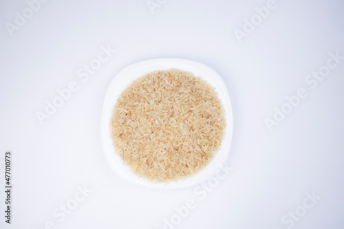 Rice. Rice in a white plate on a white background, top view. Selection of rice for meals. Choosing rice for sushi. Healthy grains. Healthy food.